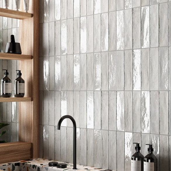 Bathroom with tiled wall, black faucet, and decorative elements.